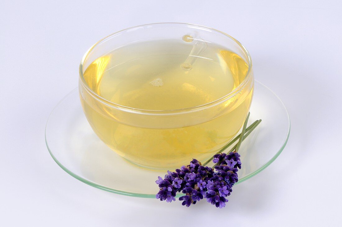 Lavender tea in glass cup, lavender flowers in saucer