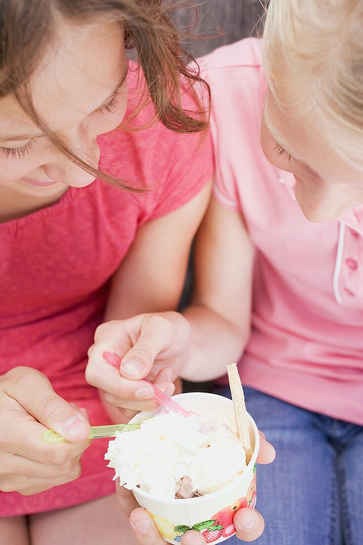 Zwei Mädchen essen zusammen einen Eisbecher