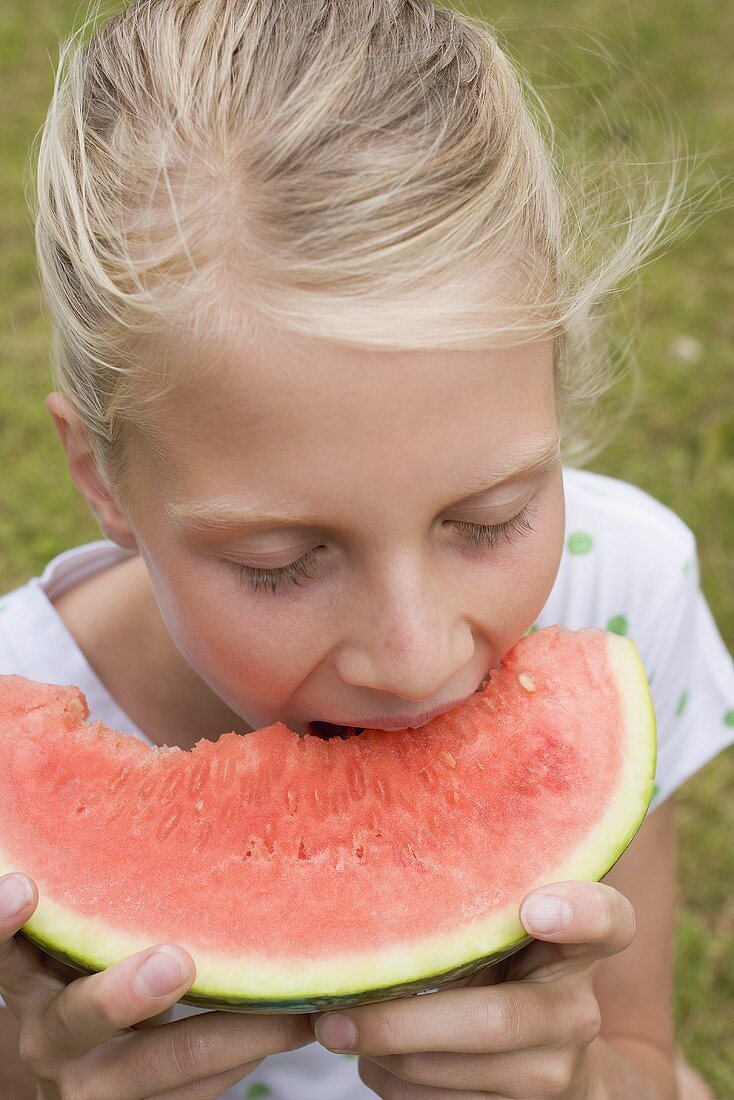 Girl eating watermelon out of doors