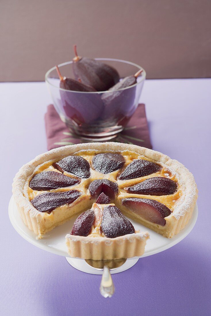 Red wine pear tart on cake stand, a piece cut
