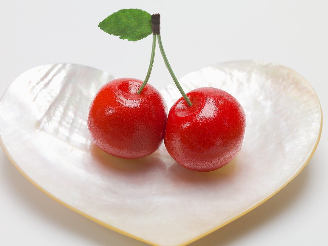 Pair of marzipan cherries in heart-shaped mother-of-pearl dish