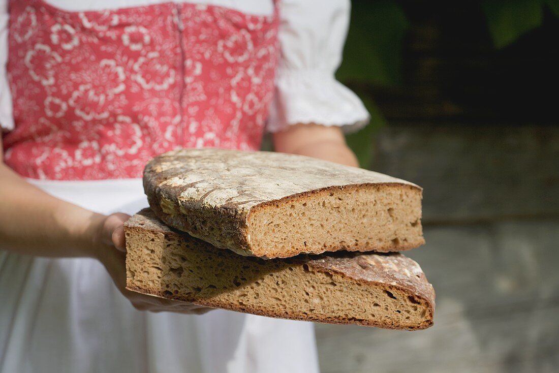 Woman in traditional costume holding coarse rye bread