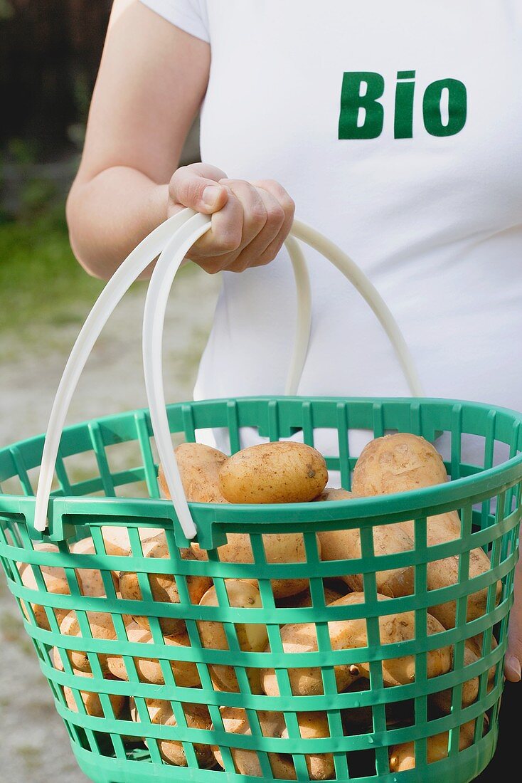 Woman carrying potatoes in a plastic basket