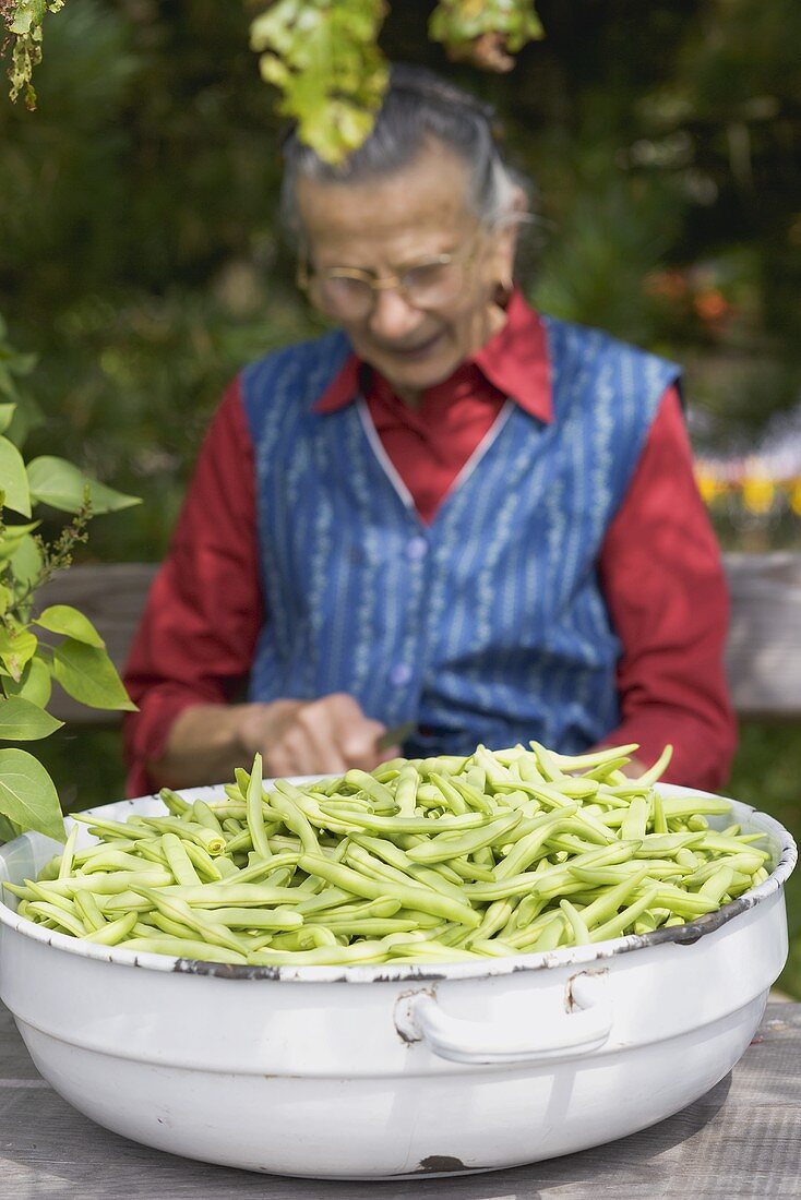 Country woman trimming green beans out of doors