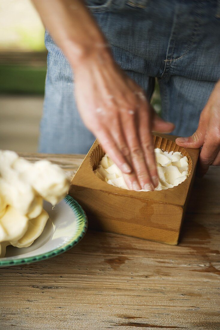 Hände drücken Bauernbutter in Holzmodel