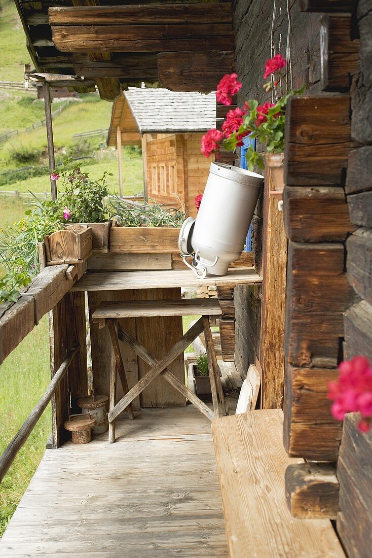 A empty milk can upside down on wooden table outside an Alpine chalet