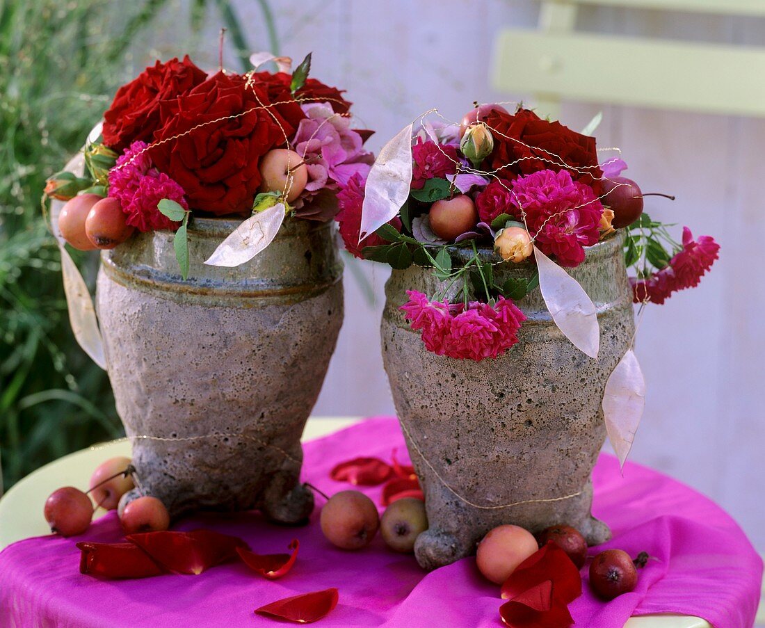 Roses & ornamental apples in two nostalgic vases on garden table