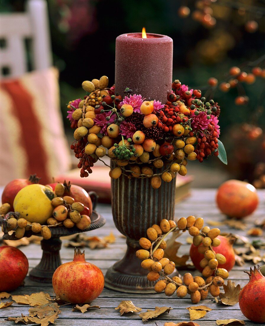 A burning candle on a table with autumn decorations