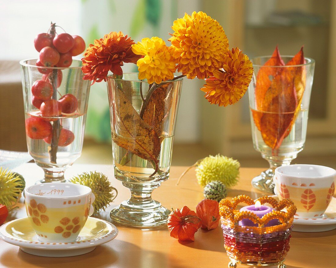Ornamental apples, chrysanthemums & foliage in wine glasses