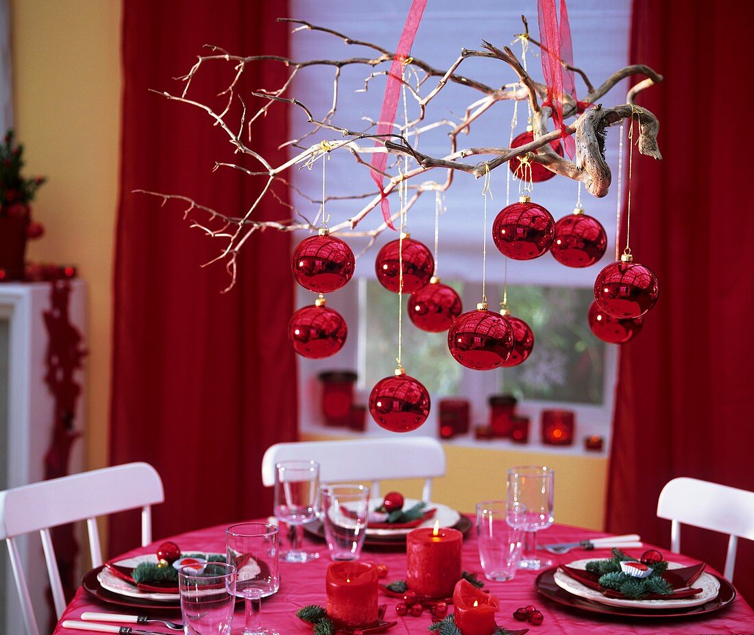 Red baubles on branch hanging over table