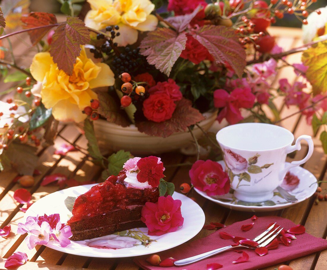 Raspberry cake with roses, cup and bowl of flowers