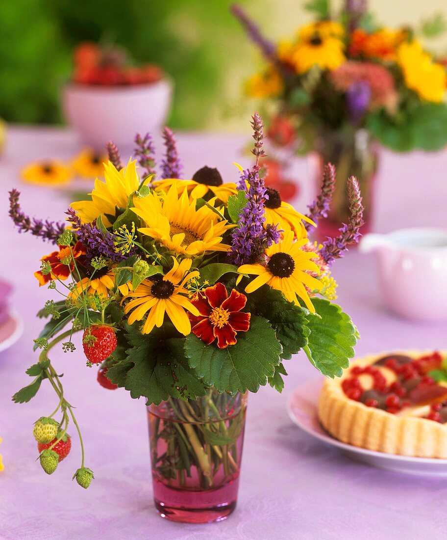 Rudbeckias, sunflowers, strawberries and dill in a glass
