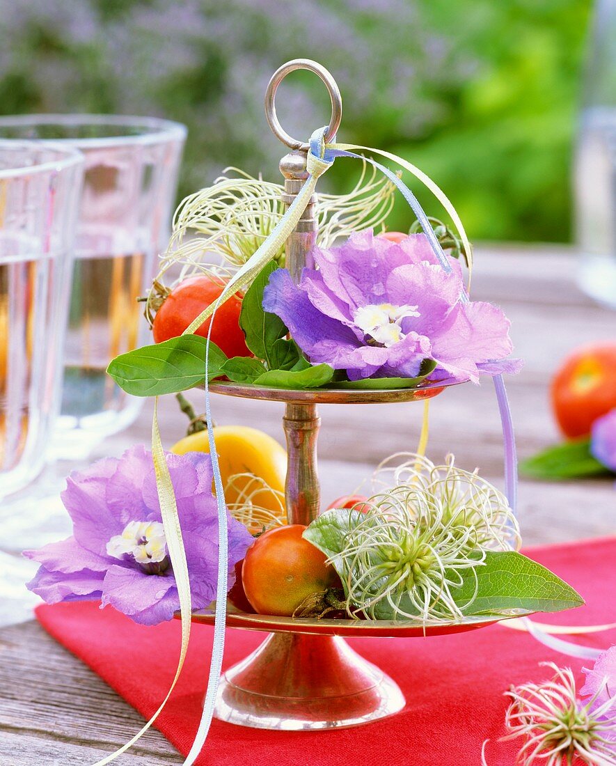 Delphiniums, clematis and basil on silver tiered stand