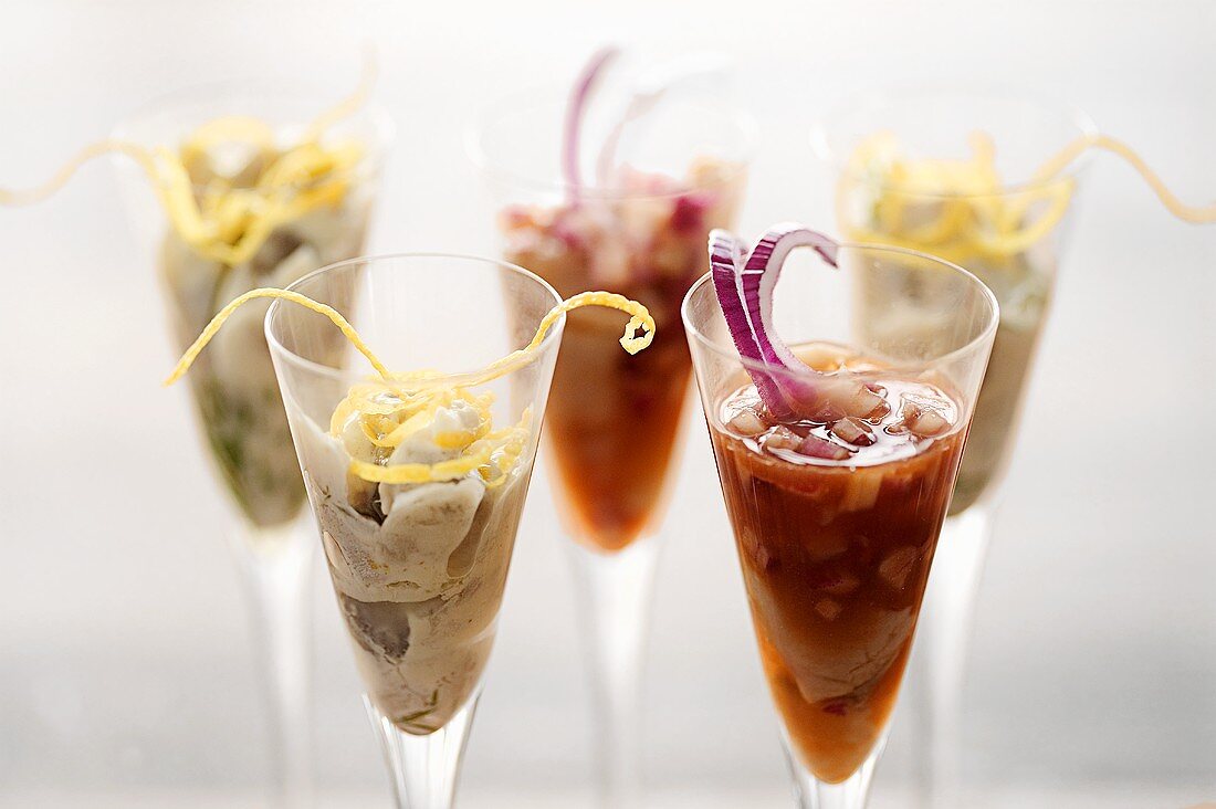 Different kinds of herring salad in cocktail glasses