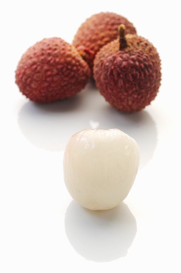 Lychees: three unpeeled and one peeled