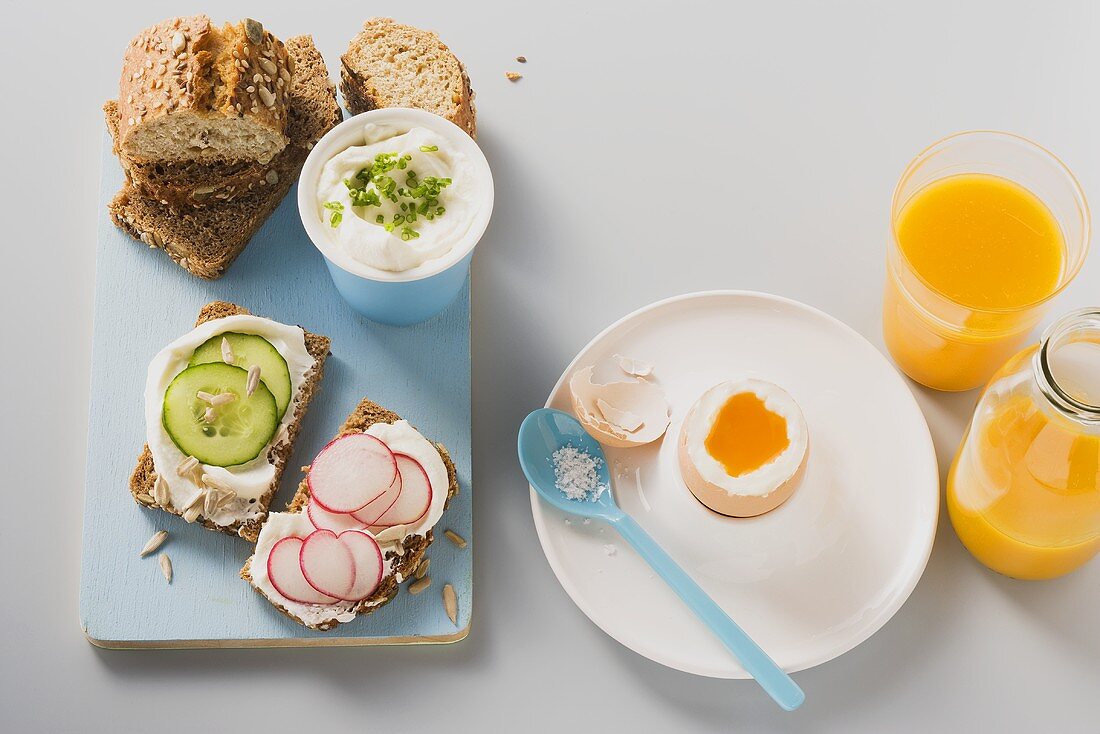 Frühstücksei und Vollkornbrote mit Magerquark, Radieschen und Gurke