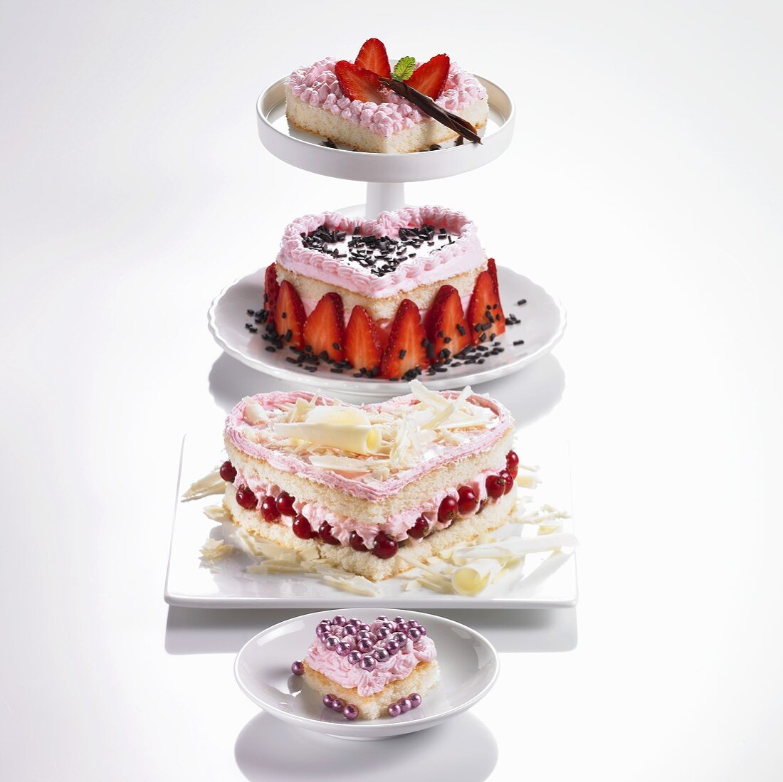 Four heart-shaped sponge cakes with redcurrants or strawberries & cream