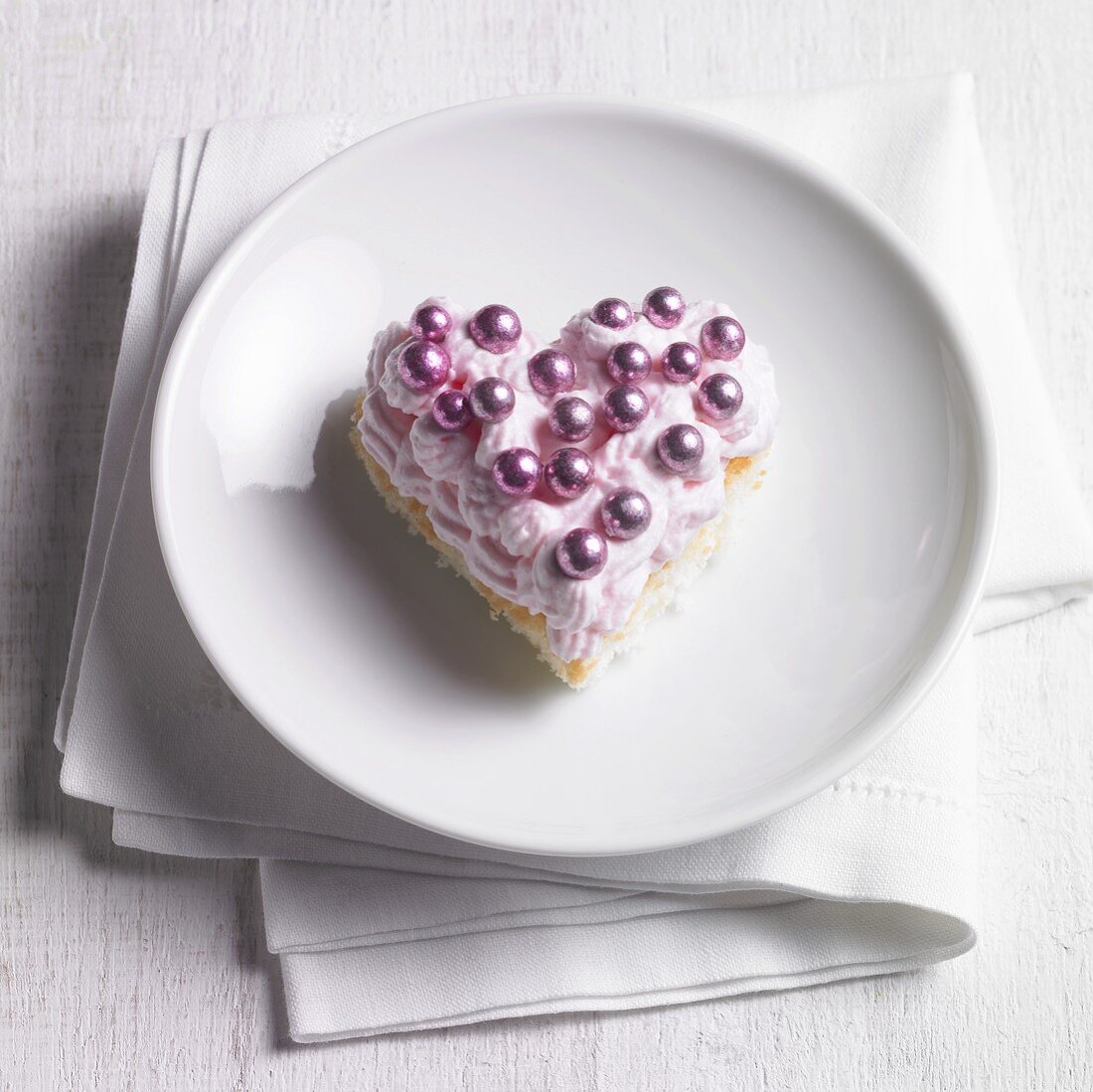 Heart-shaped sponge cake with strawberry cream and dragees