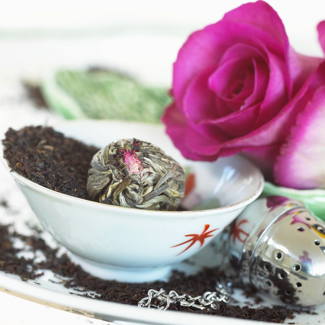 Tea leaves, flowering tea, tea infuser and pink roses