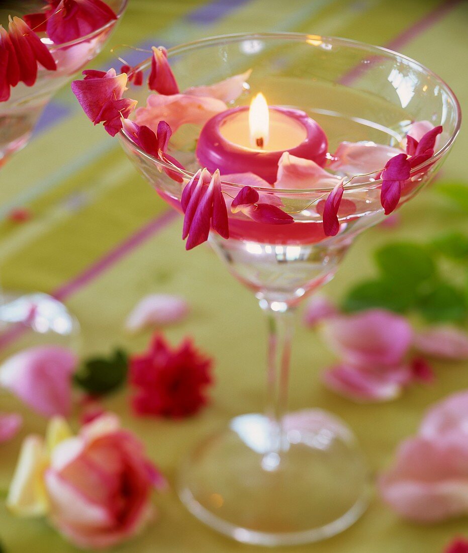 Glass with floating candle and rose petals