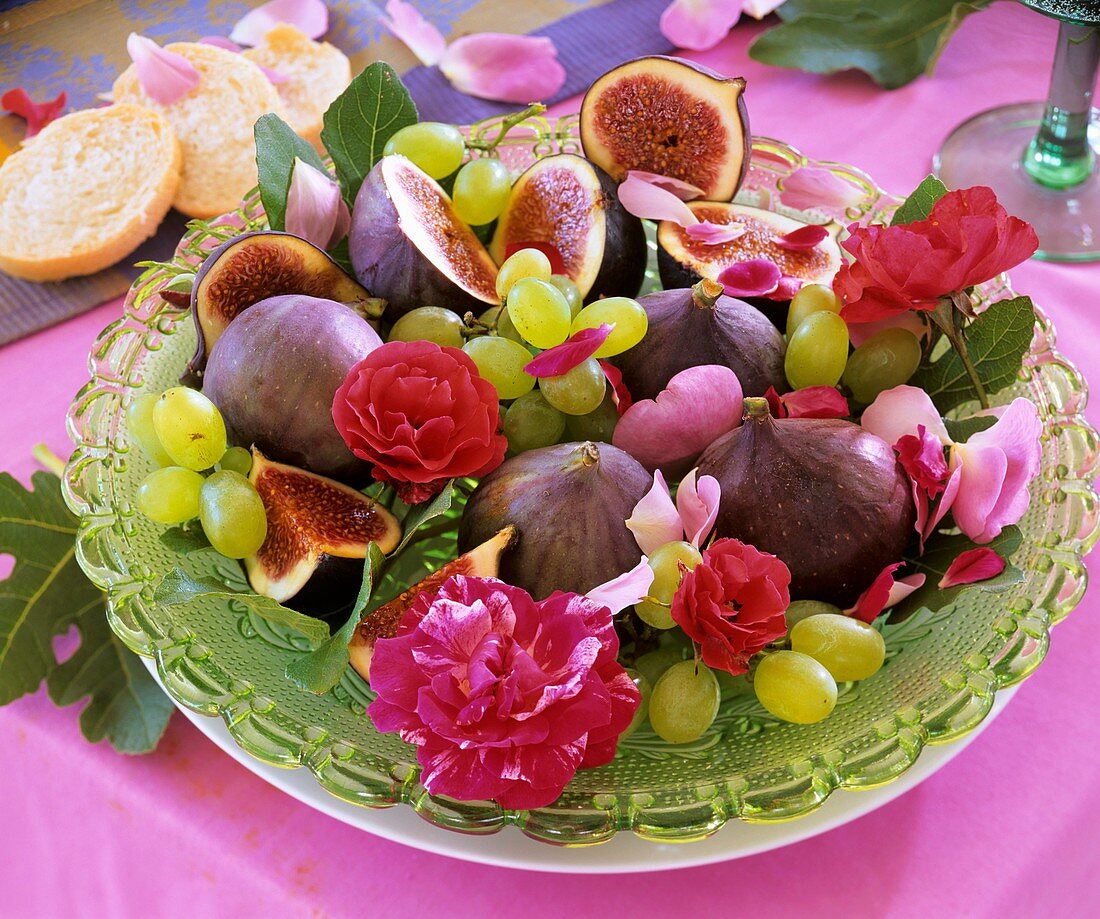 Glasteller mit Feigen, Weintrauben und Rosenblüten