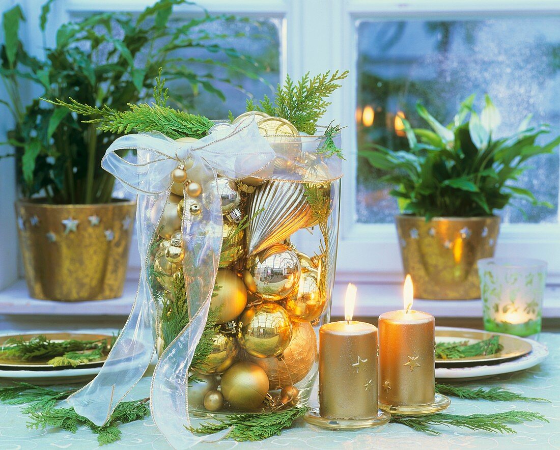 Hohes Glasgefäß gefüllt mit goldenem Baumschmuck