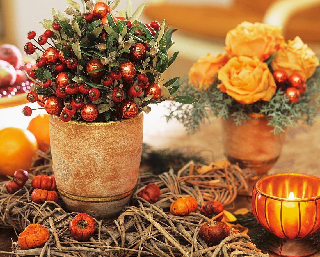 Pot of rose hips, bay leaves, glass baubles and roses