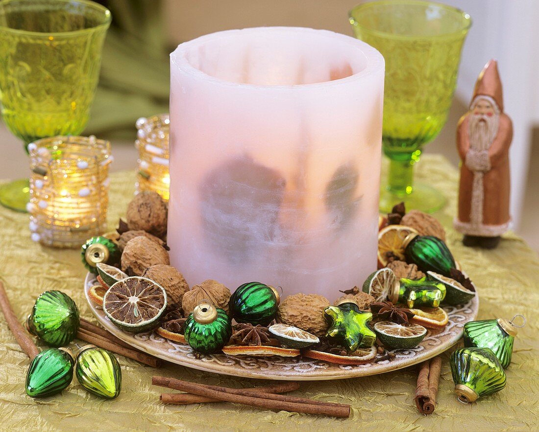 Plate with wax windlight, walnuts and tree ornaments