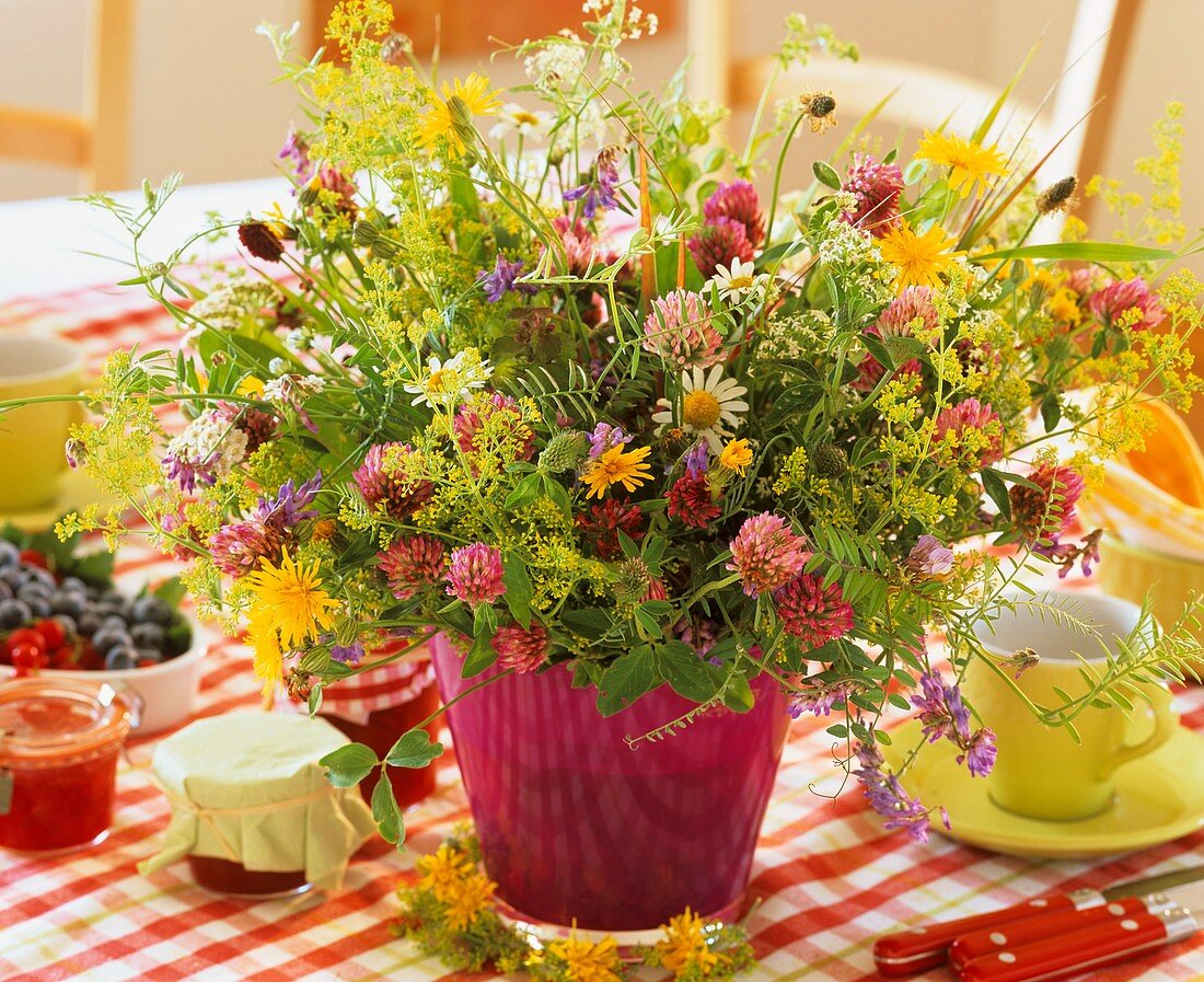 Ein Strauss aus bunten Wiesenblumen auf Frühstückstisch