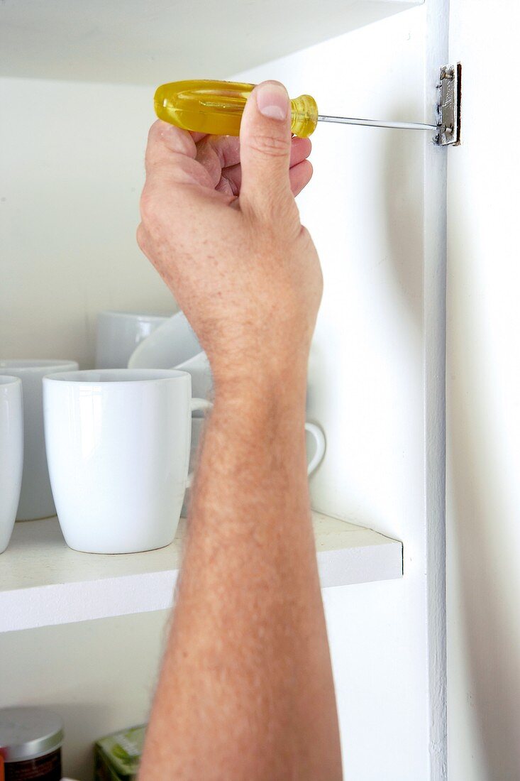 Screwing the hinge of a cupboard door