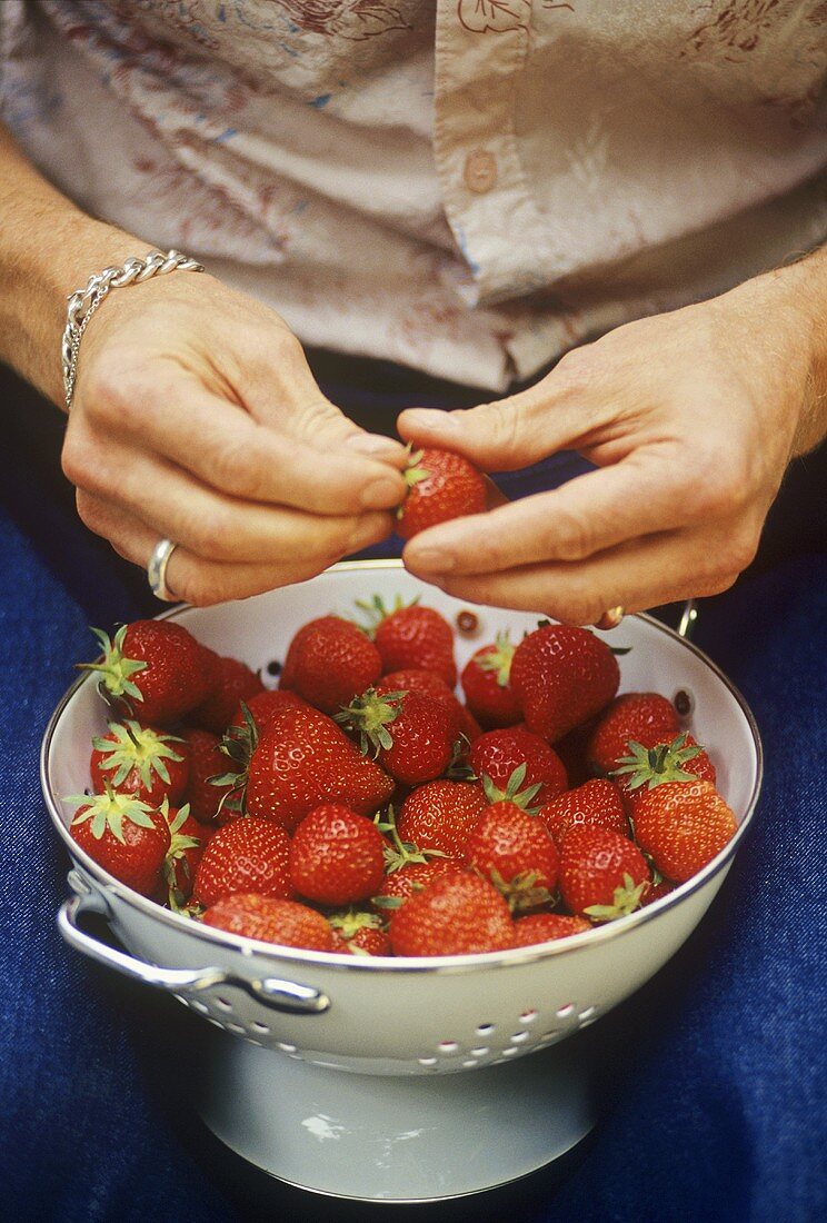 Frau hält Sieb mit frischen Erdbeeren