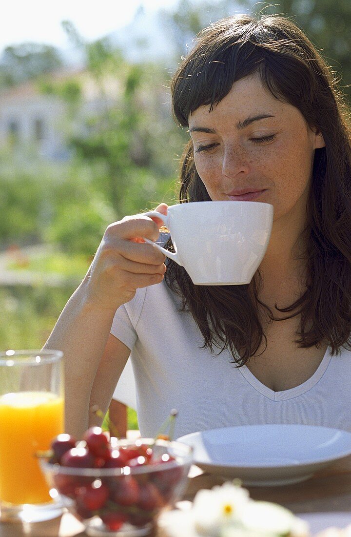 Junge Frau trinkt Tee am Frühstückstisch