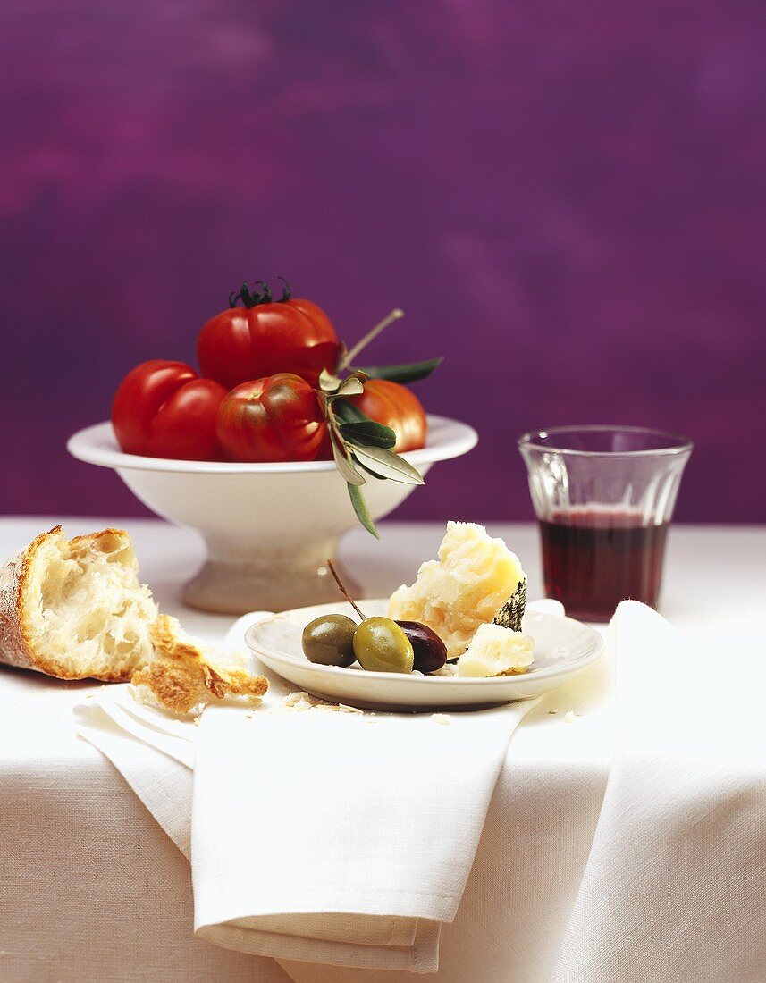 Still life: white bread, Parmesan, olives, red wine & tomatoes