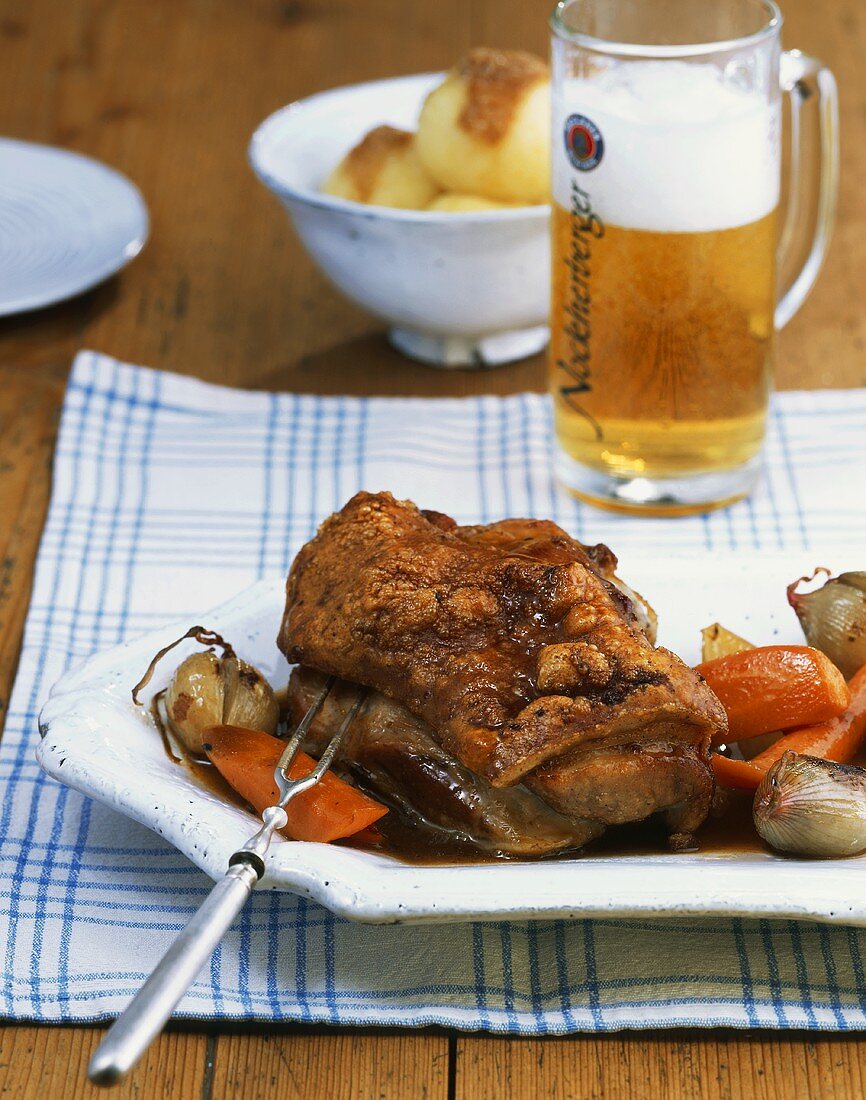 Joint of suckling pig with crackling on vegetables cooked in beer