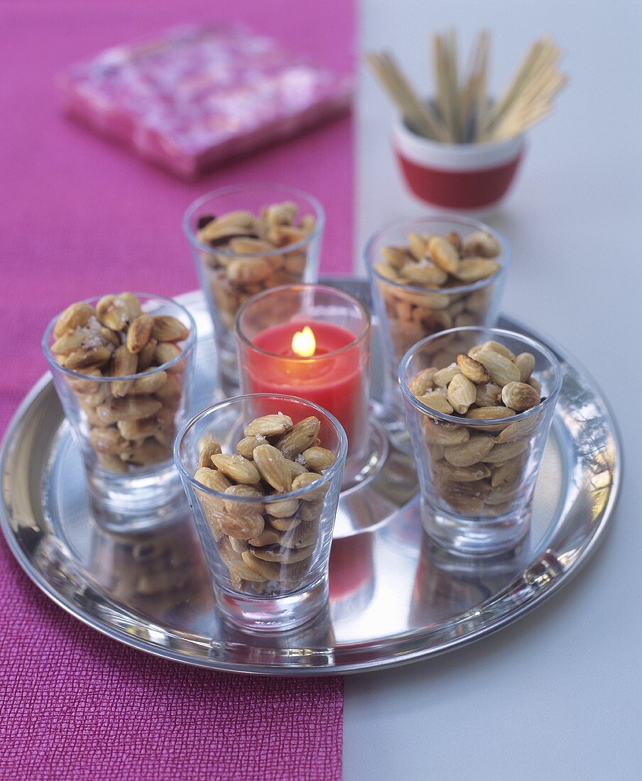 Salted almonds and candle on silver tray