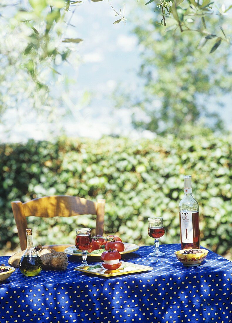 Laid table with tomatoes, mozzarella & olives out of doors