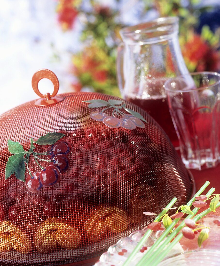 Cherry cake under food cover and cherry juice