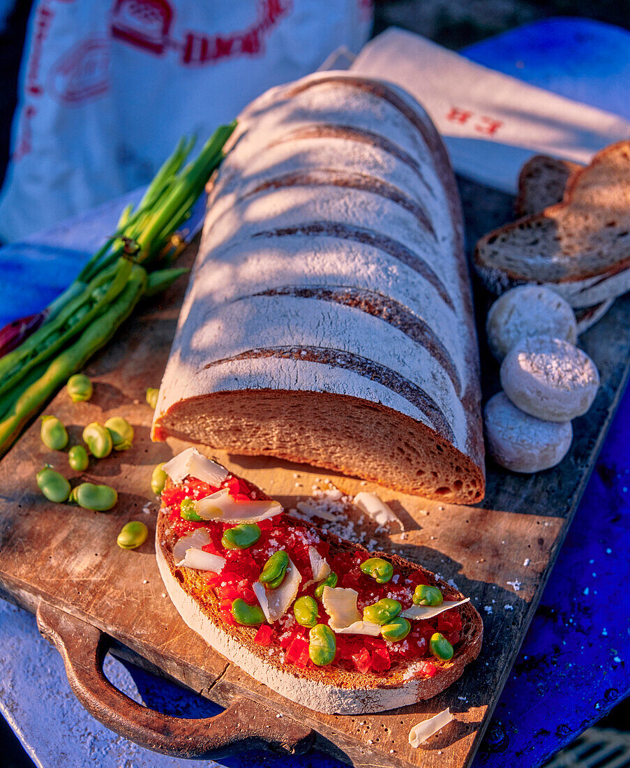 Brotscheibe mit Tomaten, Bohnen und Käse belegt