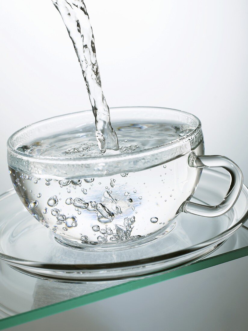 Heisses Wasser in eine Glastasse gießen