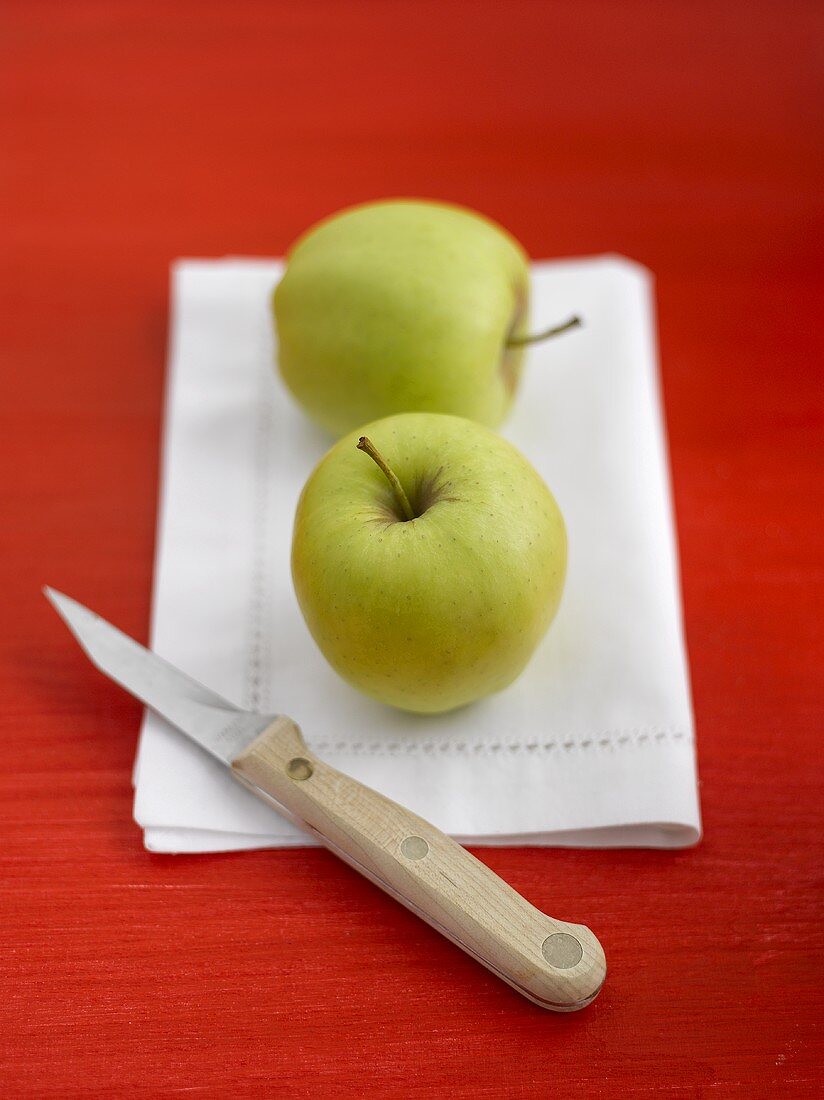 Zwei Äpfel (Sorte: Golden Delicious) mit Messer