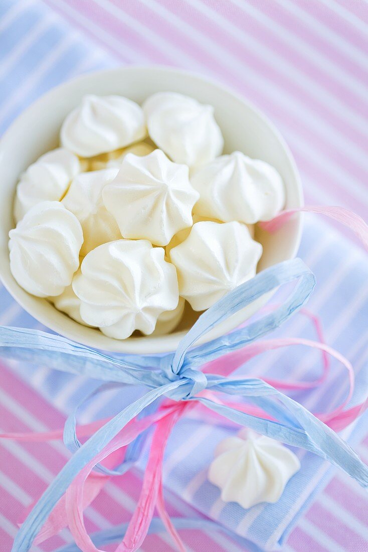 Meringues in a small bowl with a bow