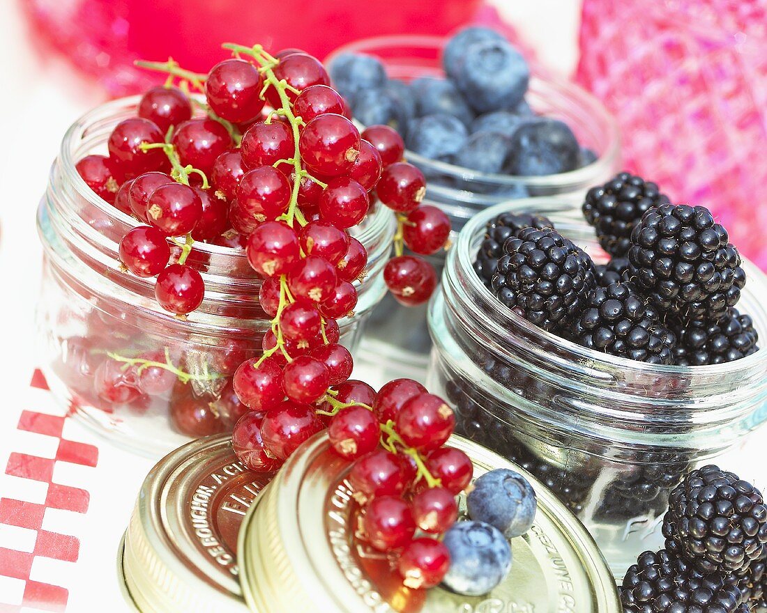 Redcurrants, blackberries and blueberries in screw-top jars