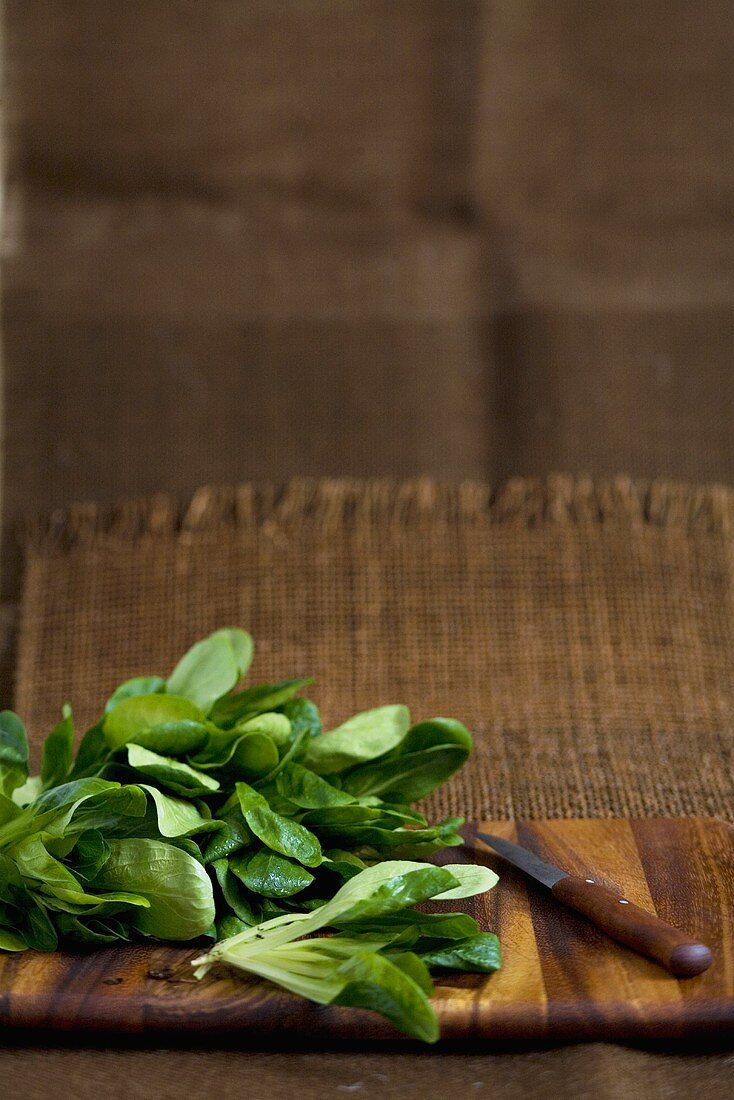 Feldsalat mit Messer auf Holzbrett