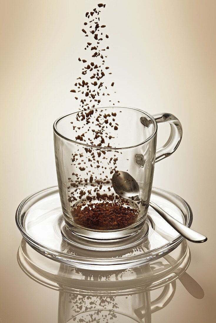 Coffee granules falling into glass cup