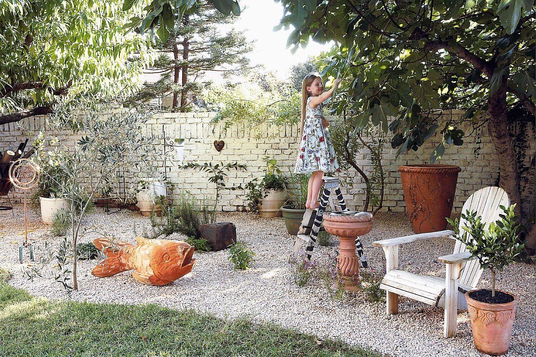 Girl standing on step ladder in garden