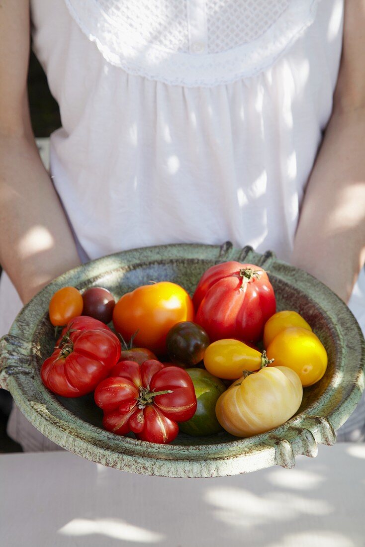 Woman holding a dish of different kinds of tomatoes