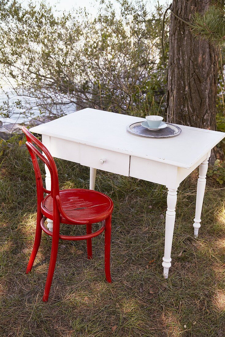 White table with red chair by lake