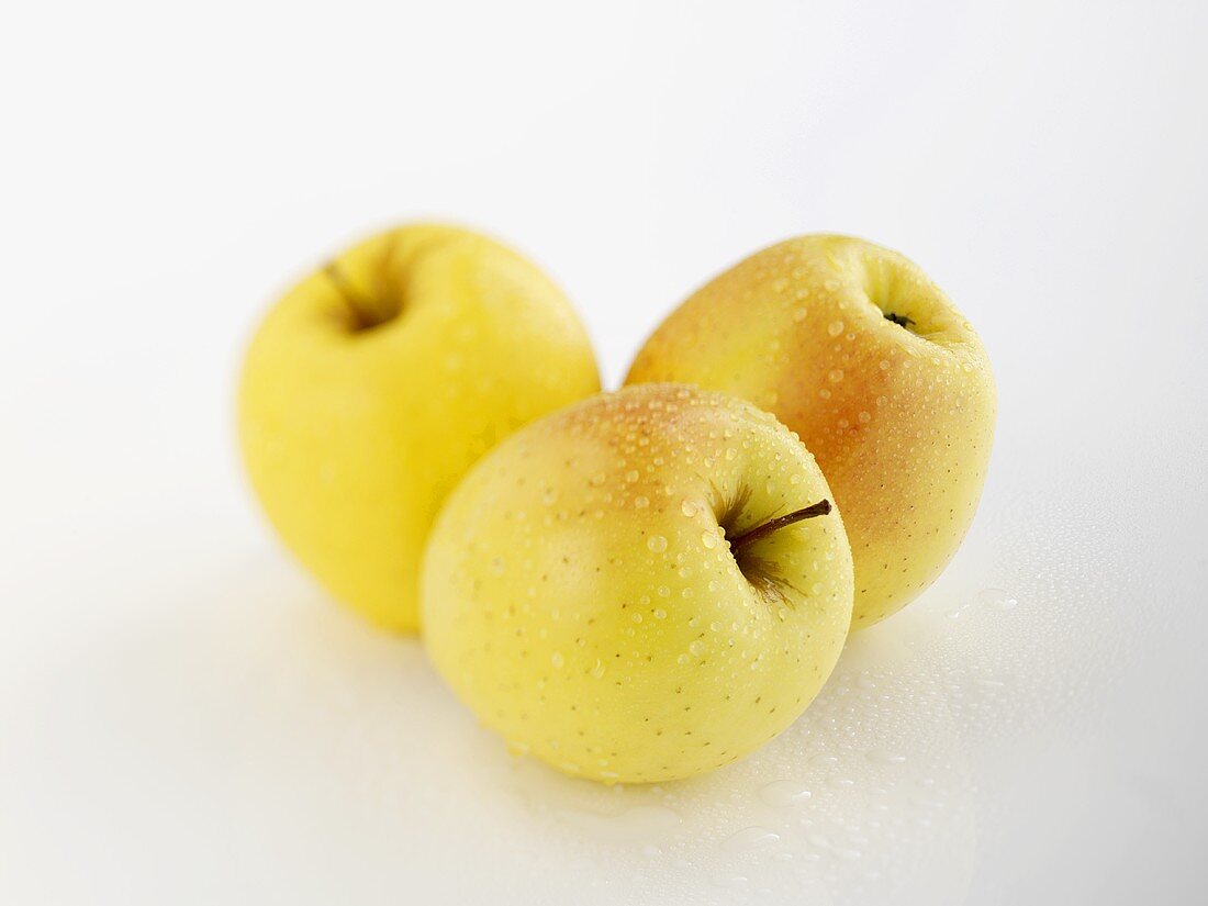 Three apples (variety 'Golden Melinda') with drops of water