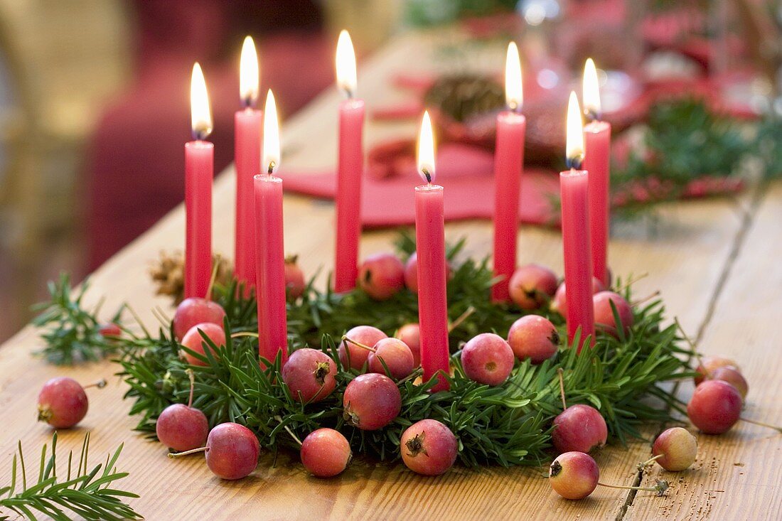 Weihnachtskranz aus Eibe mit Zieräpfeln und acht roten Kerzen