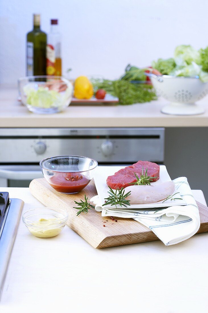 Hähnchenbrust und Rindersteak mit Zutaten auf Küchentisch